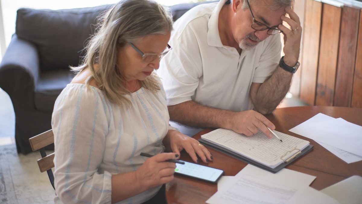 An older couple at a table going through paperwork and a checklist together at home