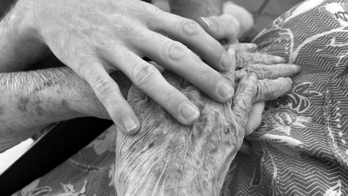 A caregiver's hand resting on an older parent's hand, the kind of daily home care TennCare CHOICES can pay for